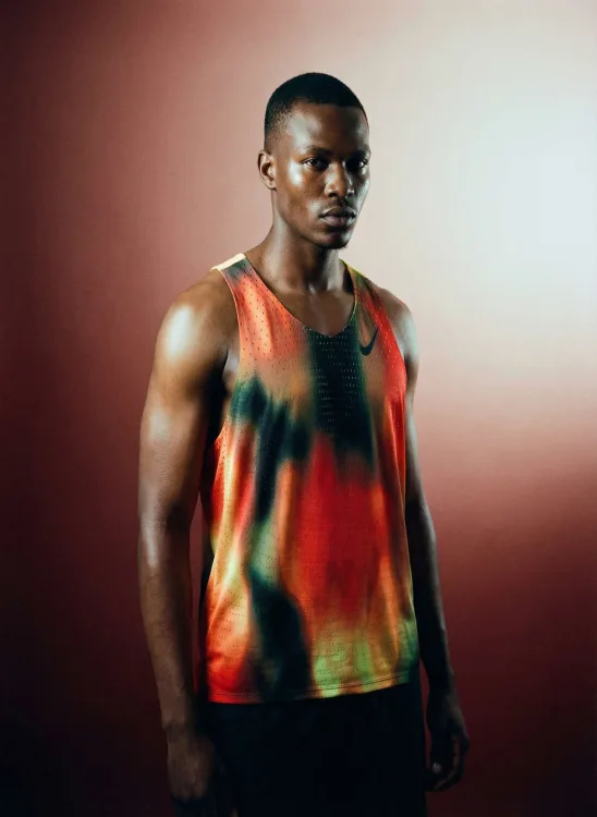 Man in a red and green tie-dye tank top in warm studio light