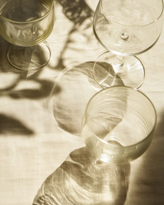 Empty wine glasses casting long shadows in warm sunlight