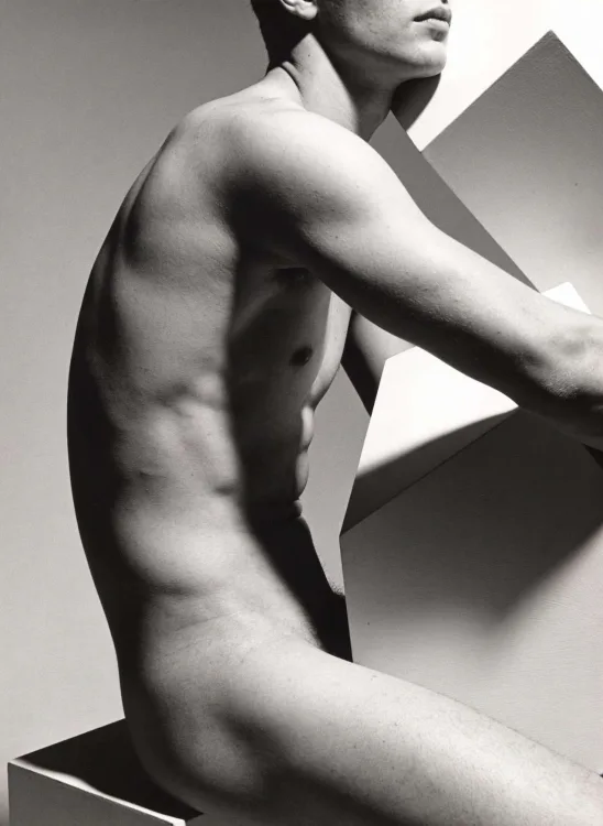 Black and white study of a male torso holding a white panel
